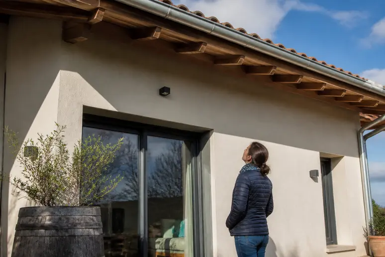 Une propriétaire française observe l'avancée de son toit, illustrant l'équilibre entre protection et esthétique de la façade.