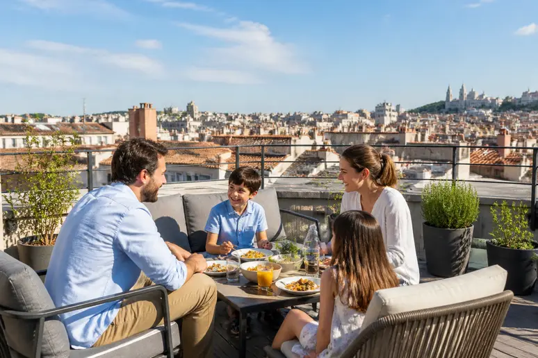 Famille dînant sur une grande terrasse sur le toit à Lyon, illustrant l'impact positif sur la valeur immobilière.