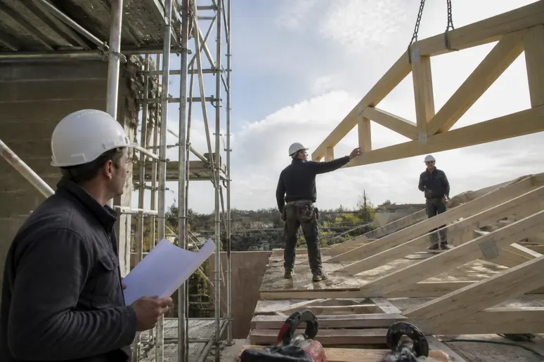Des ouvriers français installent des fermettes préfabriquées sur un chantier, démontrant la rapidité de mise en œuvre.