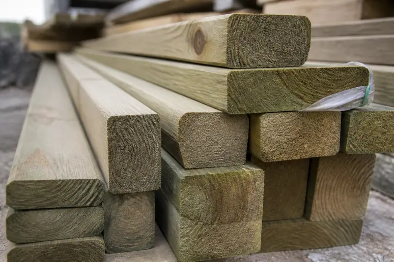 Diverses sections de liteaux en bois traité, soigneusement empilés sur un chantier, prêts à être utilisés pour une toiture.
