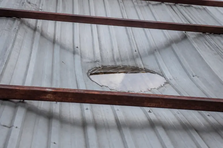 Une tôle de bac acier présente un affaissement visible entre les pannes, formant une zone d'accumulation d'eau.