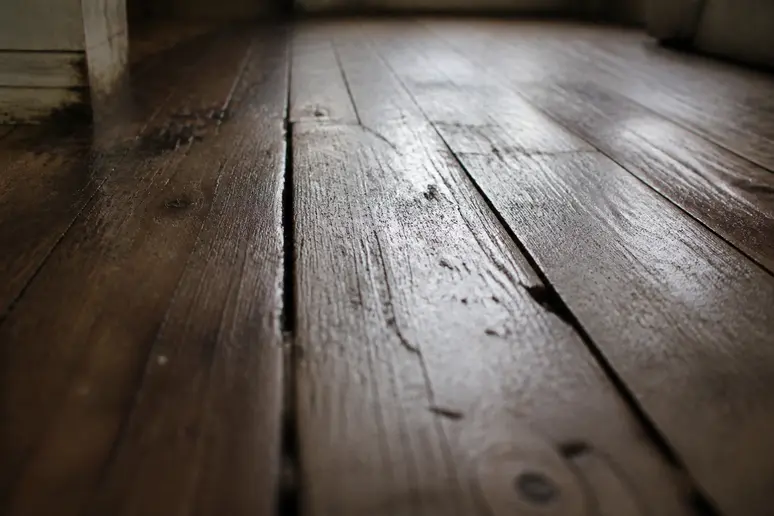 Plan rapproché sur des planches de bois anciennes et légèrement humides, révélant leur texture et leur vulnérabilité potentielle à l'humidité.