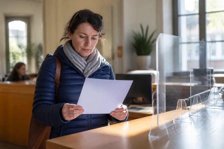 Une femme française consulte un formulaire de déclaration préalable dans une mairie, symbolisant les démarches administratives.