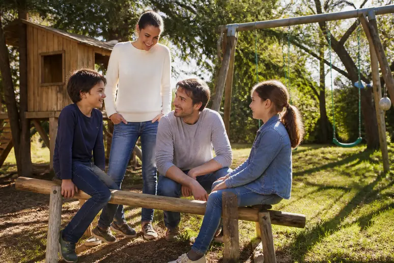 Une famille française profite de son jardin, avec des jeux pour enfants fabriqués en rondins de bois, illustrant leur polyvalence.
