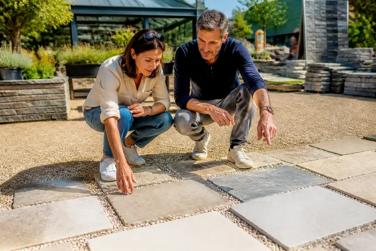 Un couple français choisit des échantillons de différentes pierres naturelles pour leur future terrasse dans un jardin.
