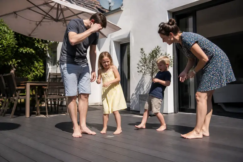 Enfant réticent à marcher sur une terrasse composite brûlante au soleil, inconvénient majeur.