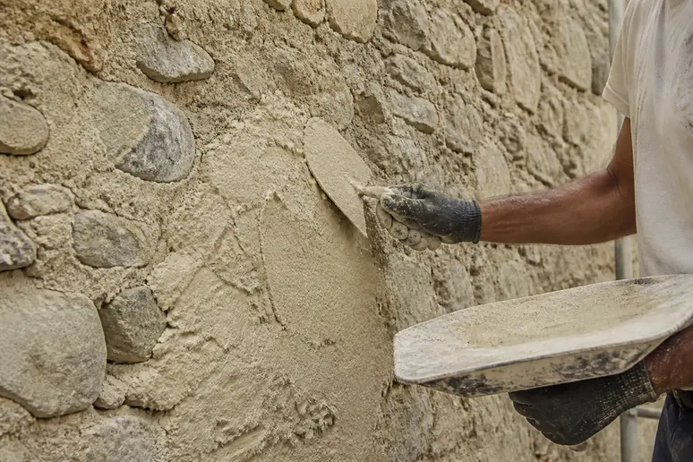 Application d'un enduit à la chaux sur un mur en pierre ancienne