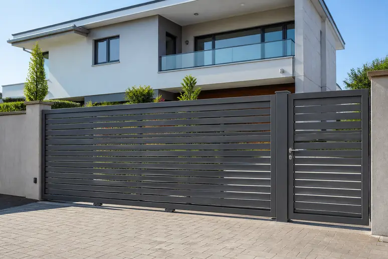 Portail coulissant en aluminium avec portillon intégré installé devant une maison.