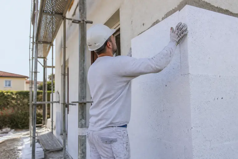 Ouvrier posant des panneaux d'isolation thermique sur la façade d'une maison individuelle dans le cadre des travaux provence eco renov