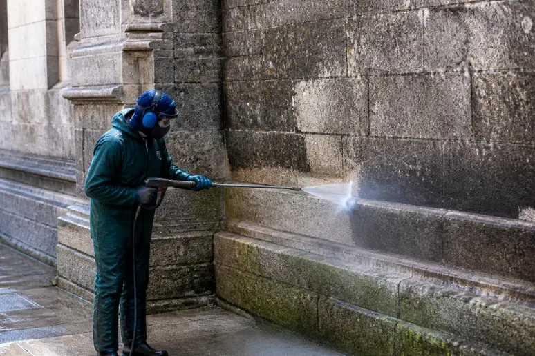 Ouvrier nettoyant un mur extérieur au jet haute pression pour la préparation du chantier
