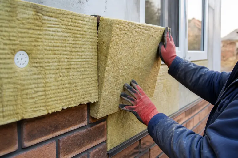 Pose de panneaux isolants sur la façade extérieure d'une maison lors des travaux